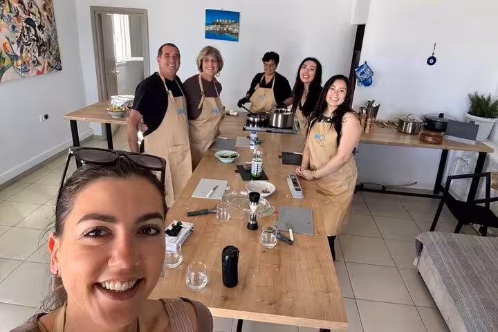 Happy small group Mykonian cooking class participants posing in aprons after cooking traditional Greek dishes