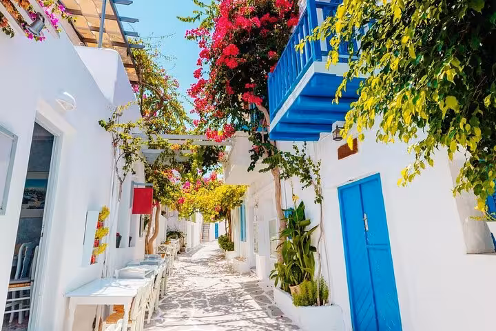 Mykonos whitewashed alley with blue doors and bougainvillea, perfect stop on a 7-day Cyclades island tour