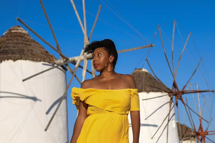 Portrait at Mykonos windmills in bright yellow dress during private photoshoot with a professional photographer