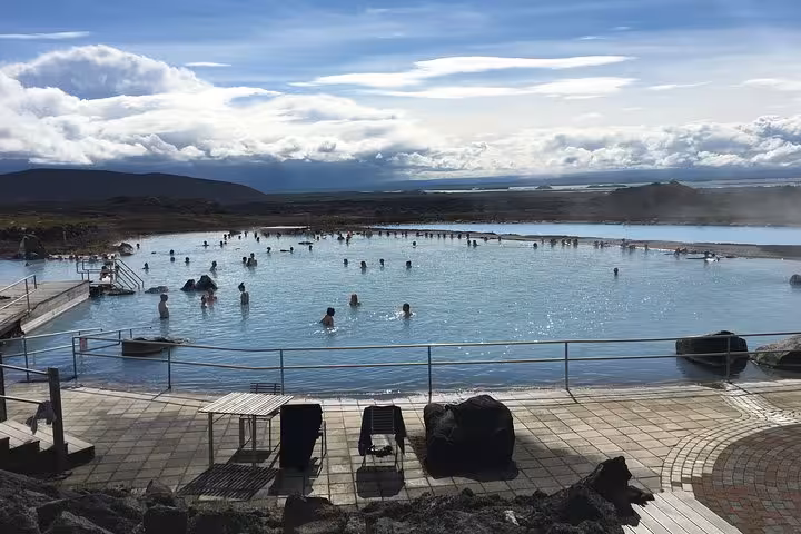 Relaxing in the serene Myvatn Nature Baths, Iceland, with visitors enjoying the warm geothermal waters under a vast sky.