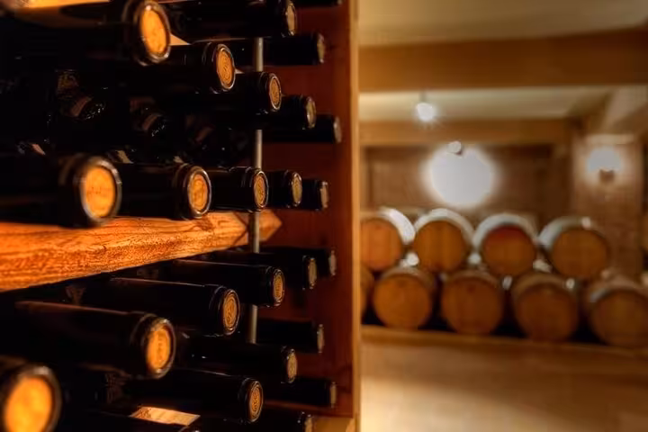 Wine bottles and oak barrels in a Peloponnese winery cellar, a gourmet stop on a private Nafplio day trip