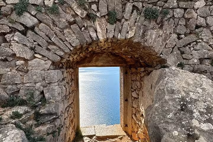 Stone archway at Nafplio Palamidi fortress opening to sea view, stop on Corinth Canal Epidaurus tour