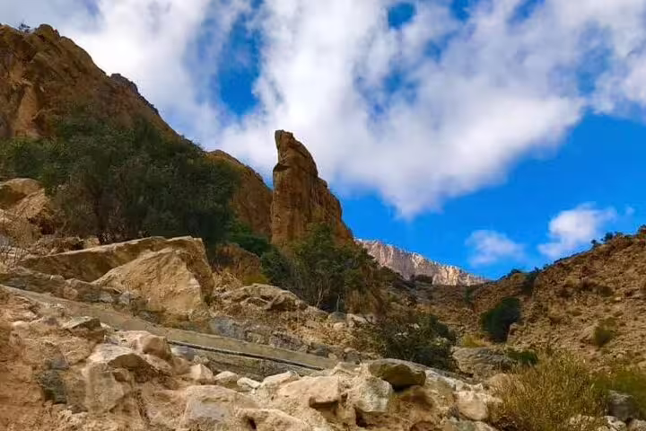 Rocky landscape with dramatic cliffs and blue sky in Nakhal Hotspring area on a full day tour.