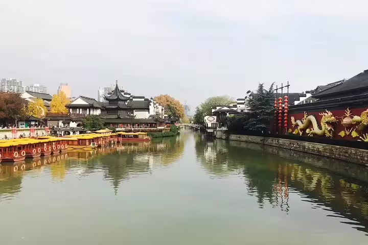 Scenic view of the Qinghuai River with traditional architecture and dragon mural in Nanjing's historic area.