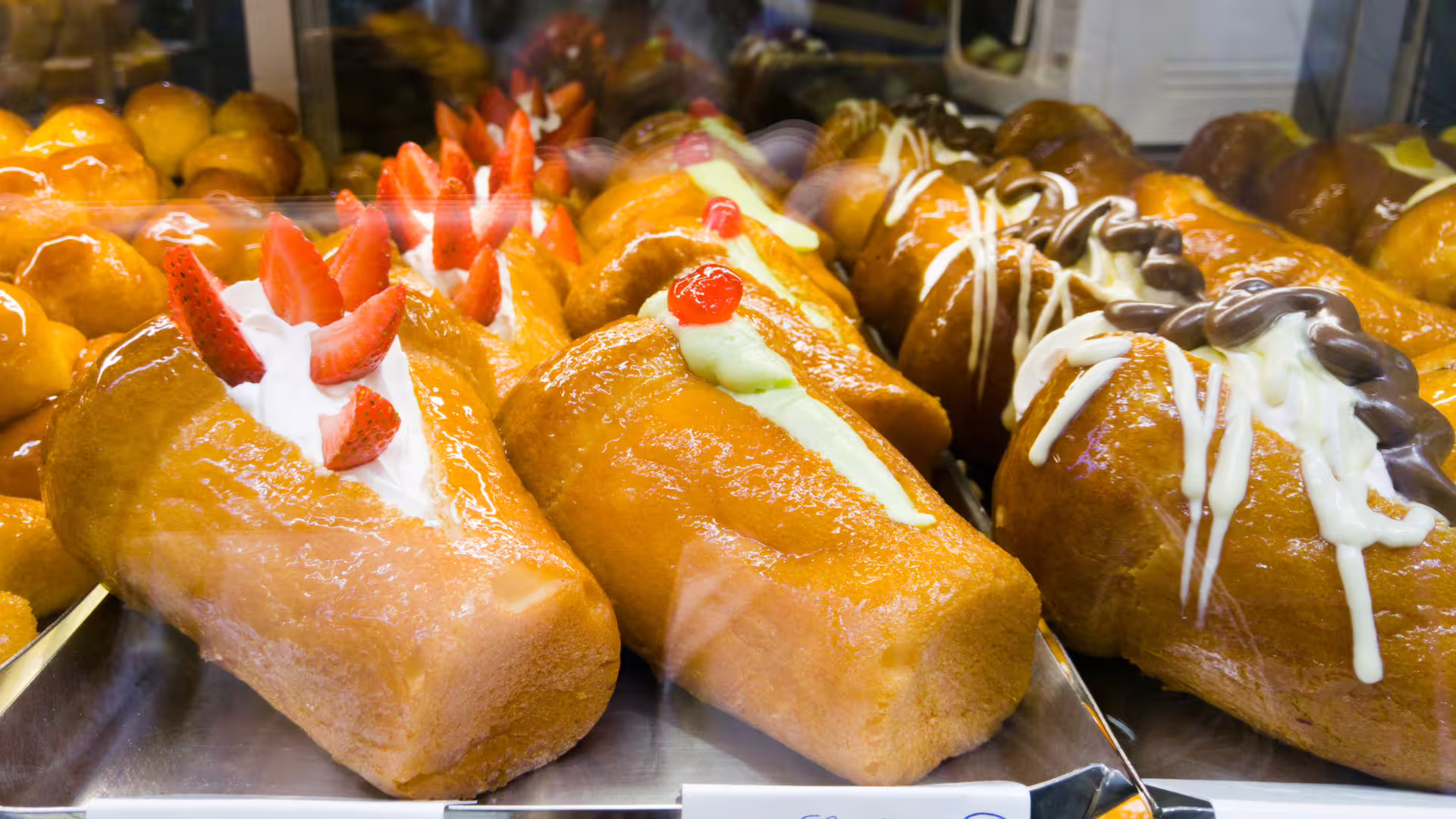 Vetrina di babà napoletani con panna, fragole e crema al cioccolato, degustazione street food nel centro storico di Napoli