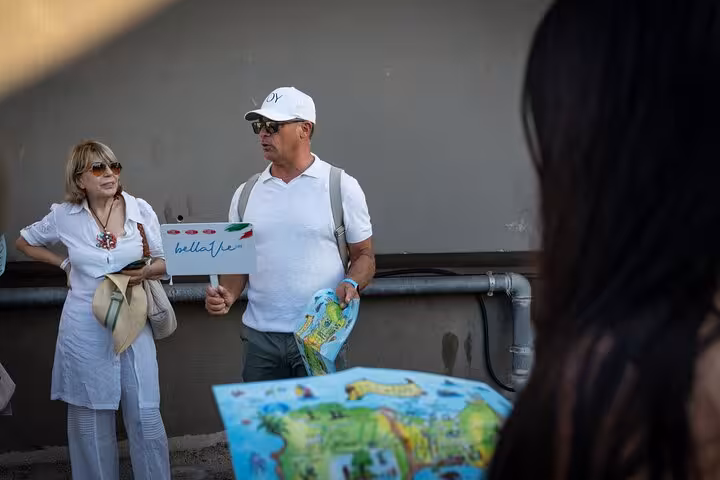 Tour guide holding a map and sign, preparing for the Blue Grotto and Faraglioni tour from Naples.