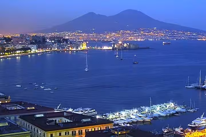 Twilight Naples city tour view of Bay of Naples, marina lights and Mount Vesuvius skyline from seafront promenade