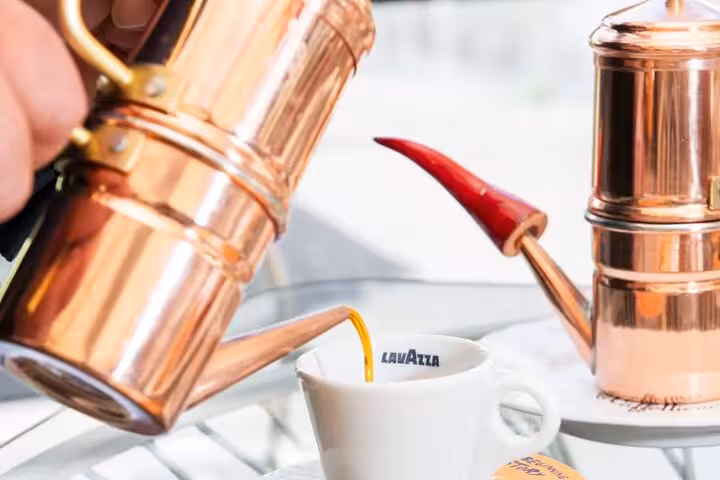 Copper espresso pot pouring rich coffee into a cup during a Naples flavors tour.