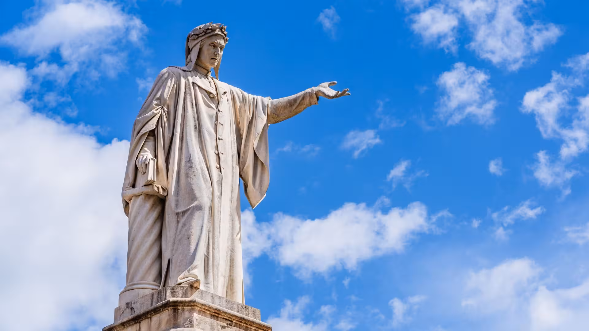 Majestic statue in Naples' historical center against a vibrant blue sky, representing classical art and history.