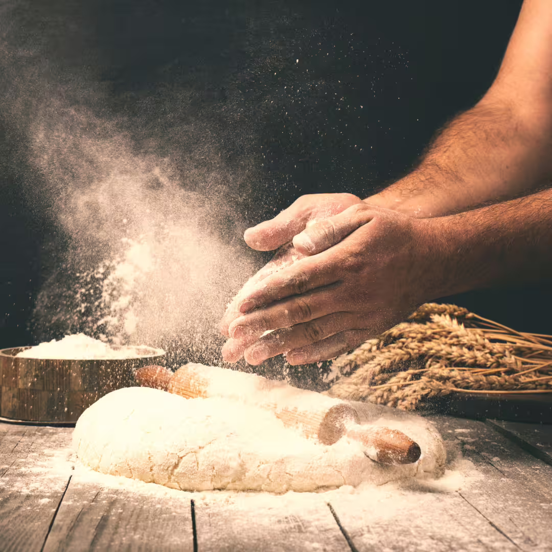 Chef’s hands dusting flour over fresh pizza dough during an authentic Naples pizza master class experience.