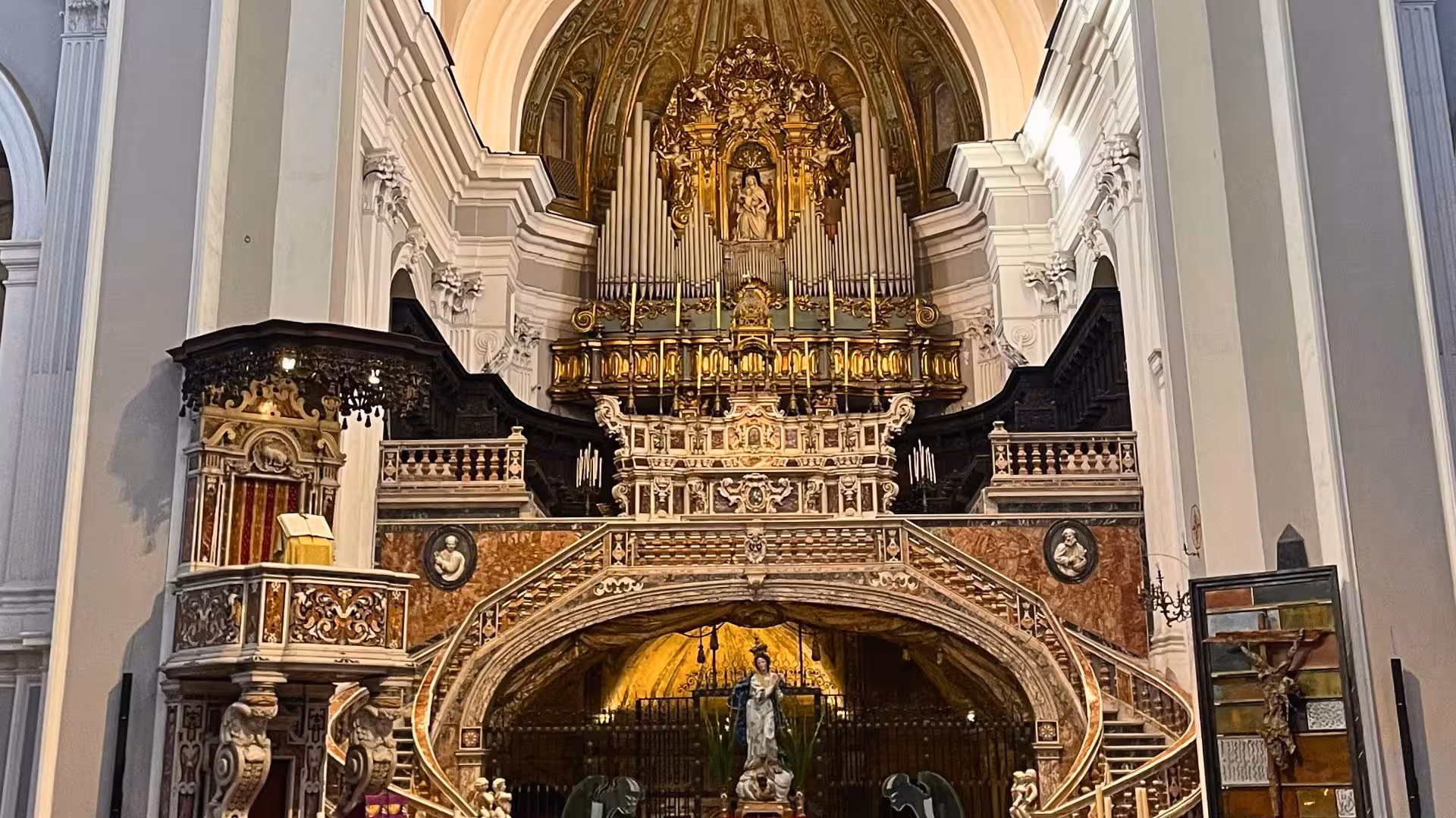 Ornate interior of a Naples church in Sanità district, featuring intricate carvings, golden altar, and religious statues.