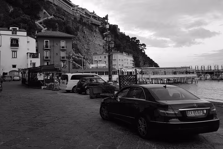 Black and white image of a car parked near Sorrento harbor, ideal for private transfer from Naples hotel, airport, or train station.