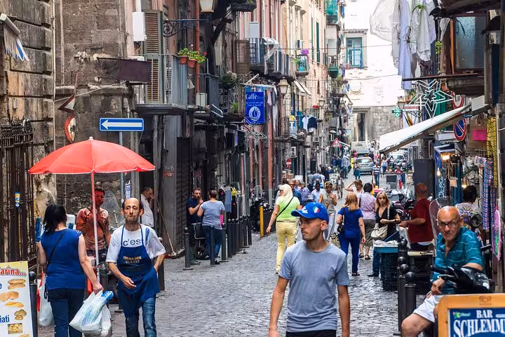 Bustling street scene in Naples with locals and tourists exploring vibrant markets and historic buildings.