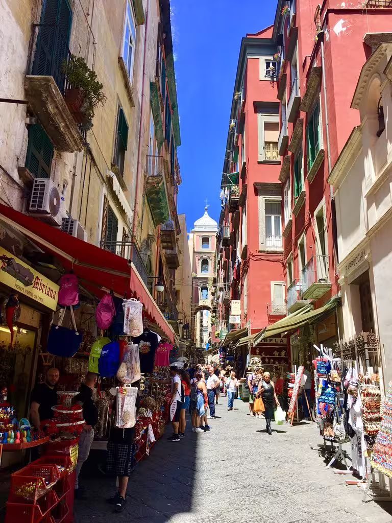 Colorful Naples street market with souvenir stalls and historic buildings, ideal stop on Pompeii group tour