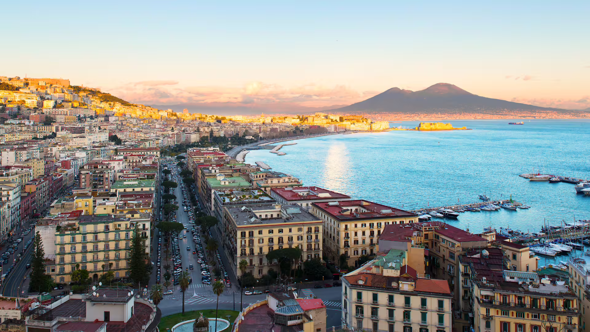 Veduta panoramica di Napoli al tramonto con Lungomare, Castel dell’Ovo e Vesuvio, tappa del tour guidato centro storico