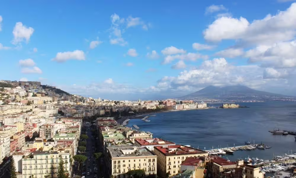 Panoramic view of Naples waterfront and Mount Vesuvius under blue skies, highlight of a 2-day Naples sightseeing itinerary
