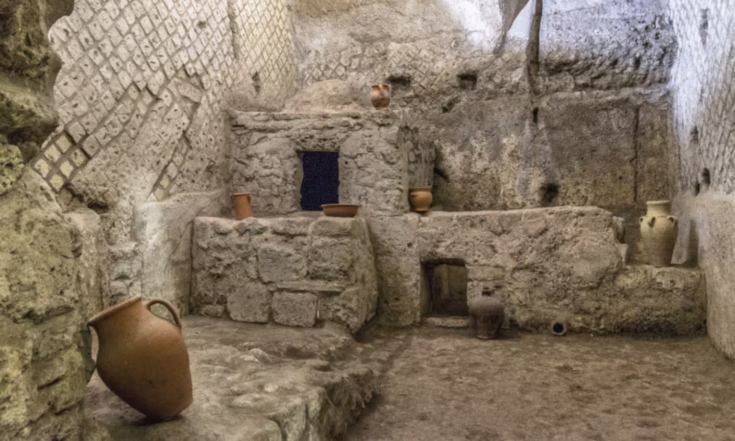 Excavated underground chamber with stone walls and clay amphorae in Napoli Sotterranea on a 2‑day Naples history tour