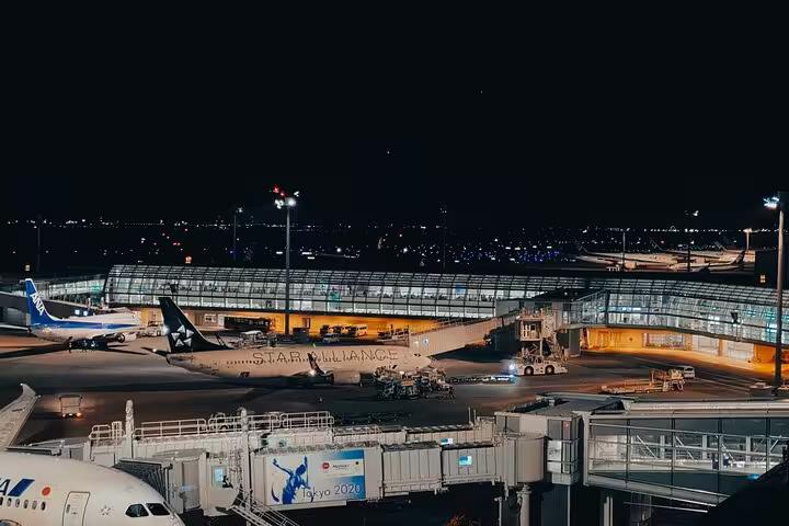Night view of Narita Airport with parked airplanes, highlighting convenient private transfer services to Tokyo hotels.