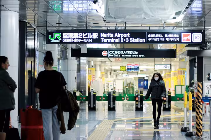 Travelers at Narita Airport Terminal 2-3 Station entrance, highlighting convenient access for private transfers to hotels.