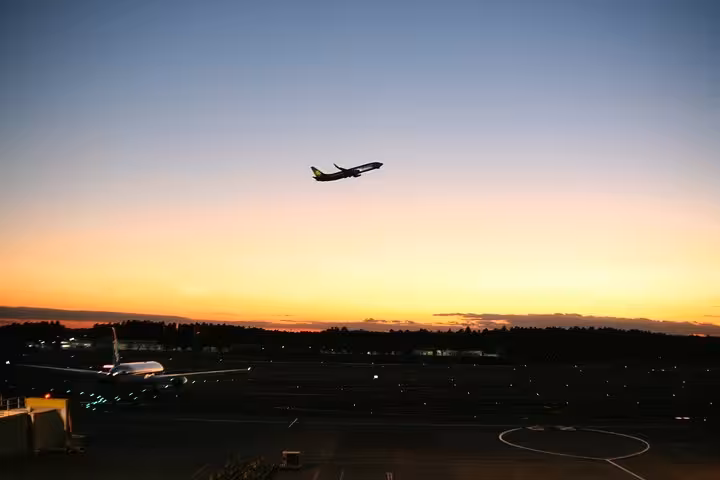 Airplane taking off against a stunning sunset at Narita Airport, perfect imagery for private hotel transfer services.