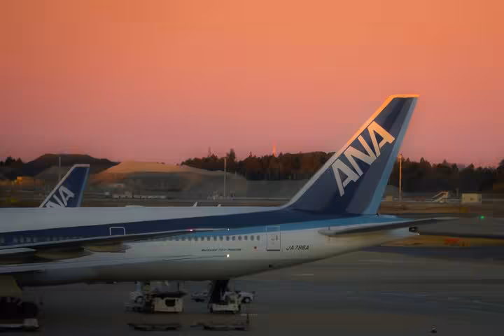 ANA airplane parked at Narita Airport during a vibrant sunset, ideal for private transfer to Tokyo hotel or Airbnb.