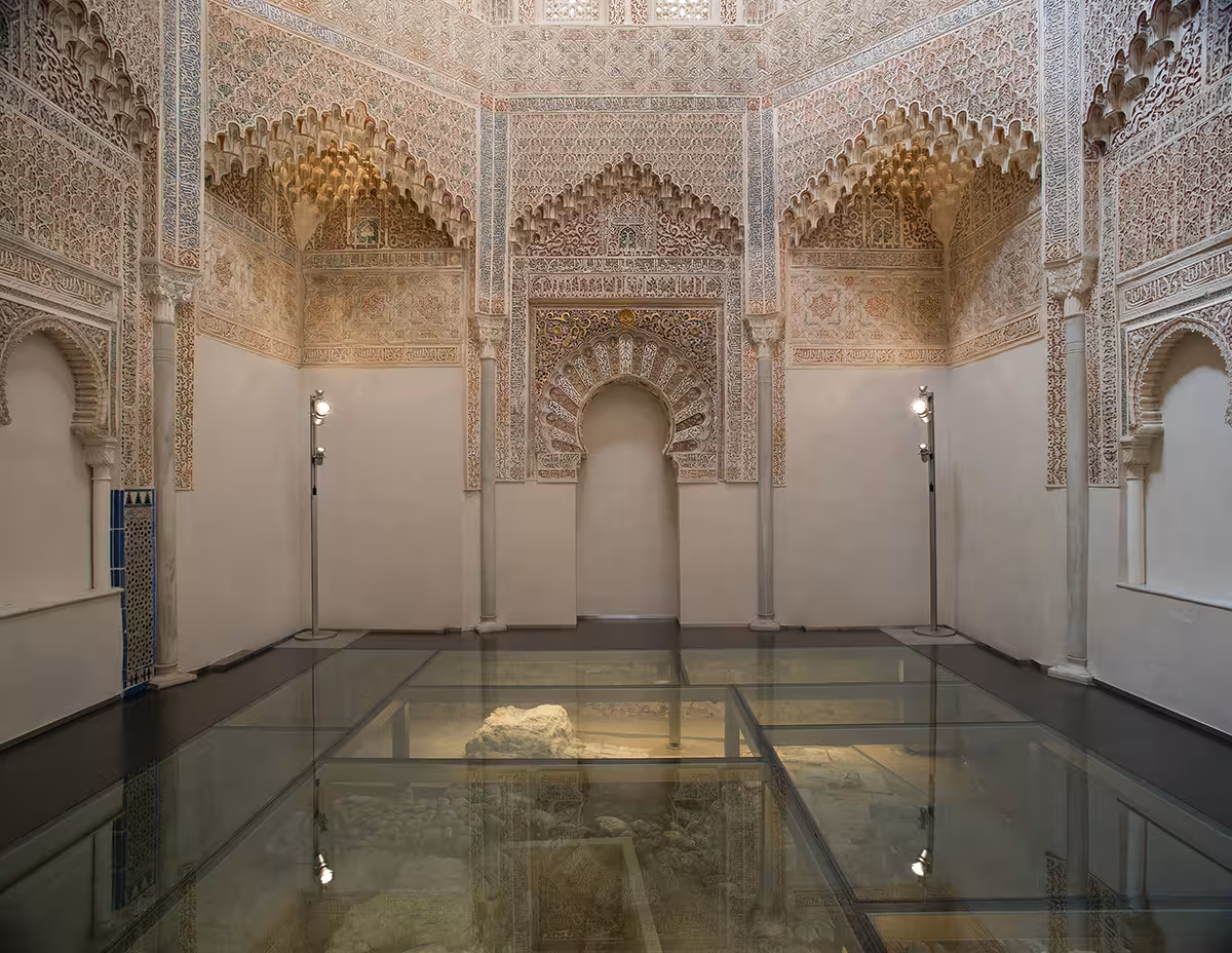 Intricate Moorish architecture inside the Nasrid Palaces at the Alhambra, featuring ornate arches and detailed stucco work.