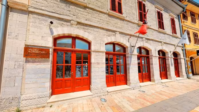 Exterior of the National Museum in Kruje with striking red doors and stone architecture.