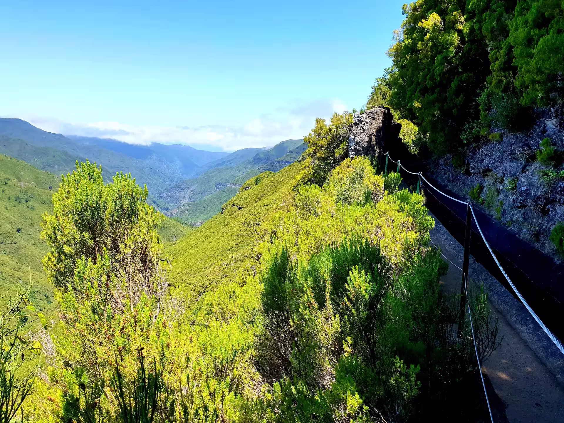 Scenic hiking trail along lush green hills with panoramic mountain views, ideal for nature lovers and adventurers.