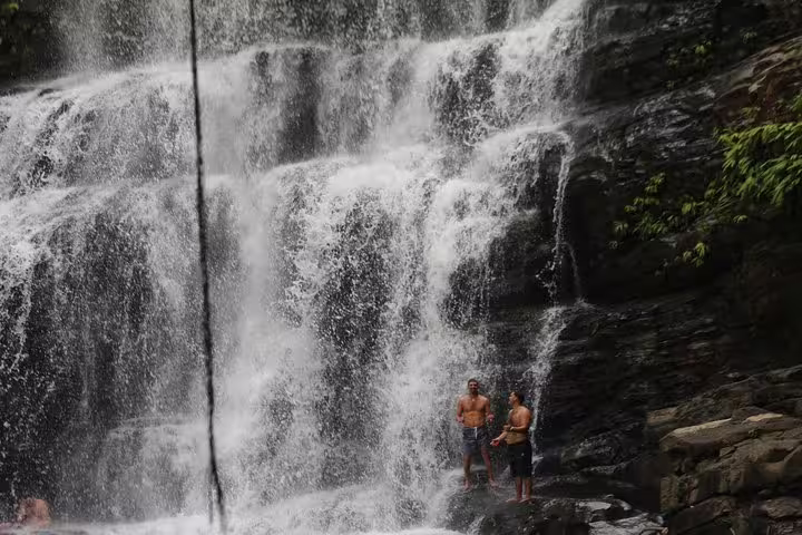 Visitors standing at the base of the majestic Nauyaca Waterfalls, experiencing the refreshing cascade in Costa Rica.