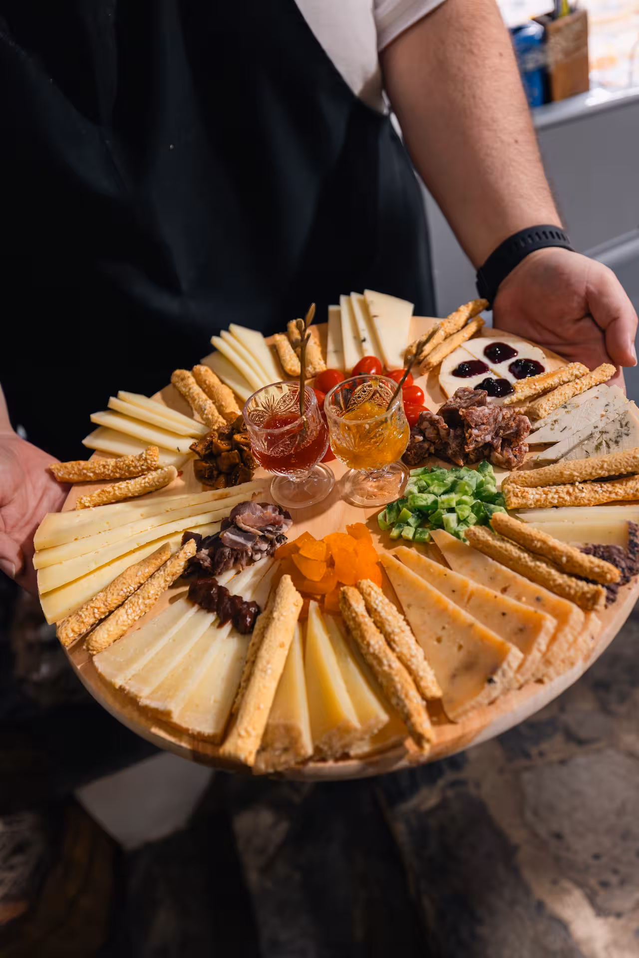 Server holding Naxos cheese tasting board with local spreads and breadsticks during Munch Around Naxos Town walk