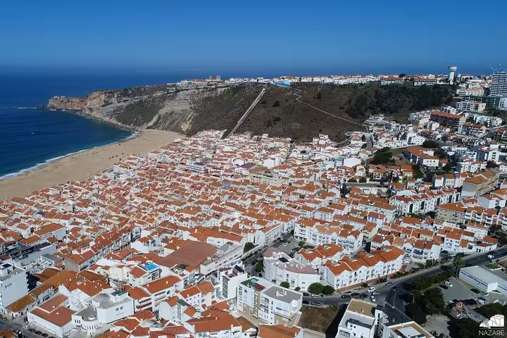 Aerial view of Nazaré beach and red-roofed town on Portugal coast, scenic stop on Lisbon to Porto tour