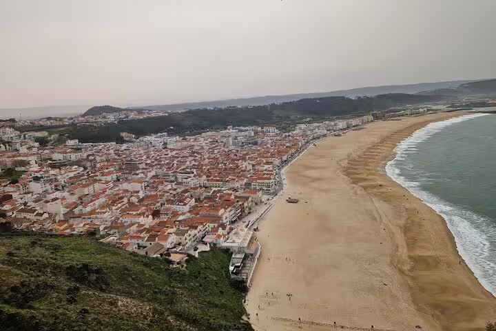Stunning aerial view of Nazaré beach and town, a picturesque stop on the Porto to Lisbon itinerary.