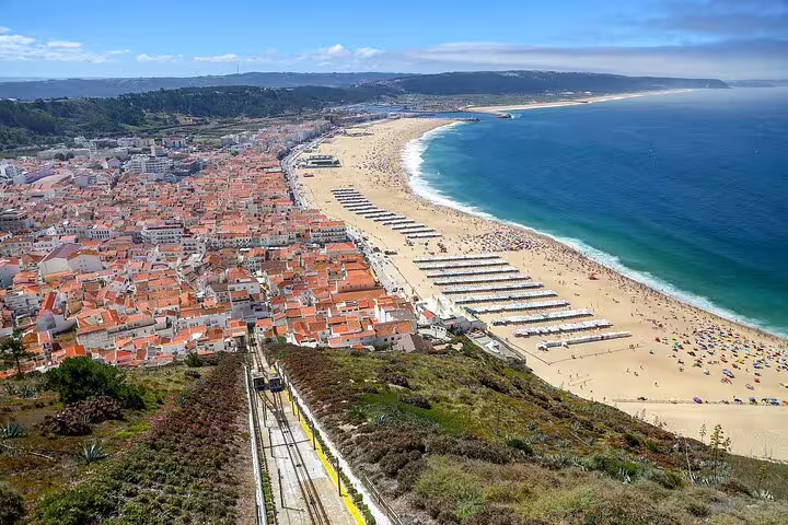 Panoramic view of Nazaré beach with vibrant rooftops and scenic coastline, a top attraction on the Porto to Lisbon tour.