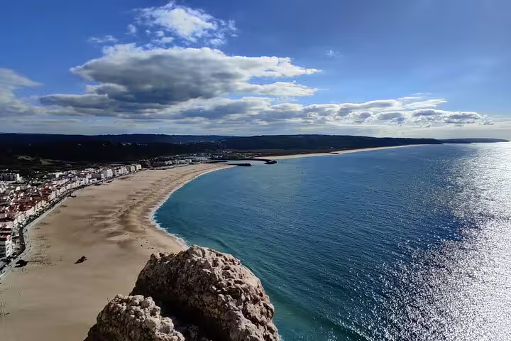 Stunning view of Nazaré beach with golden sands and sparkling Atlantic Ocean, perfect for a private day tour in Portugal.
