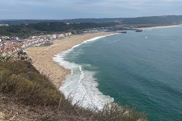 Scenic view of Nazaré's expansive sandy beach and Atlantic waves, perfect for surfing and relaxation.