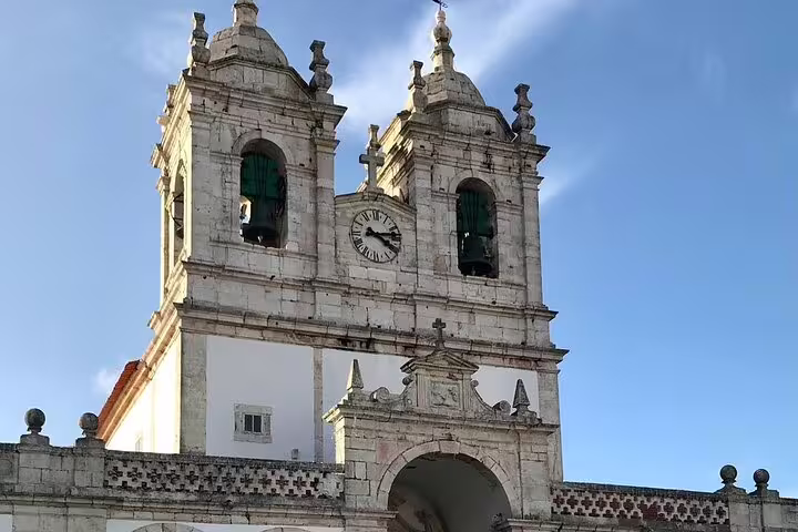 Historic church facade in Nazaré with twin bell towers under a clear blue sky, featured in the Fátima, Nazaré, and Óbidos tour.