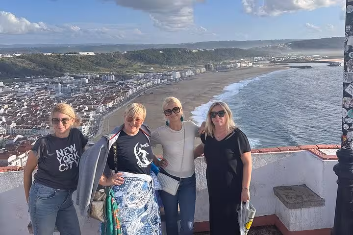 Tourists enjoying the scenic ocean view from the cliffs of Nazaré, famous for its breathtaking coastline.