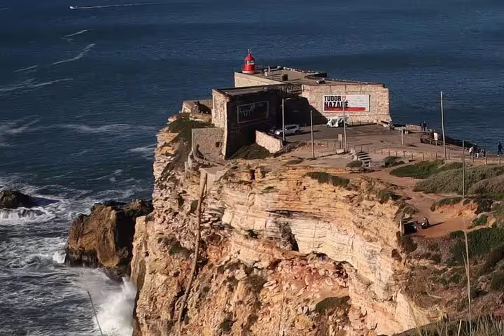 Scenic view of Nazaré's iconic cliffside lighthouse overlooking the Atlantic Ocean, featured in the Fátima, Nazaré, and Óbidos full-day tour.