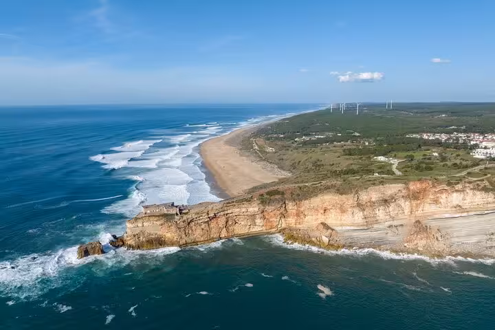 Aerial view of Nazare's stunning coastline with cliffs and sandy beaches, perfect for a scenic car tour.