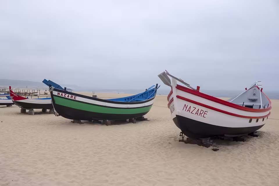 Colorful traditional fishing boats on the sandy shores of Nazaré, Portugal, ready for the next adventure.