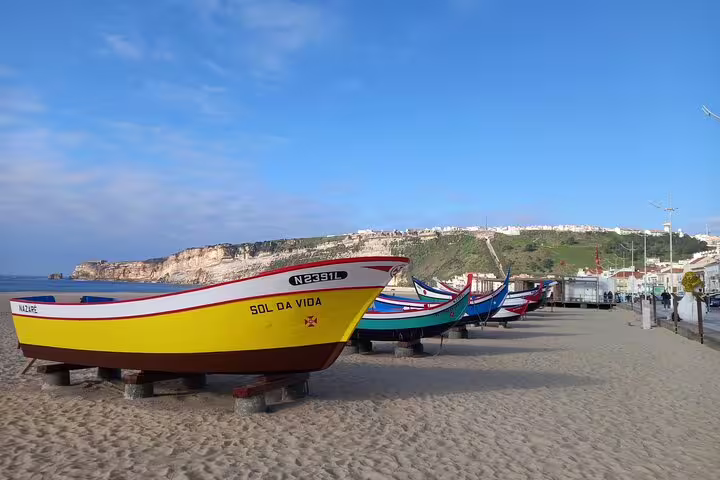 Colorful fishing boats lined up on Nazare beach, a scenic stop on Fatima-Nazare-Obidos day tour.