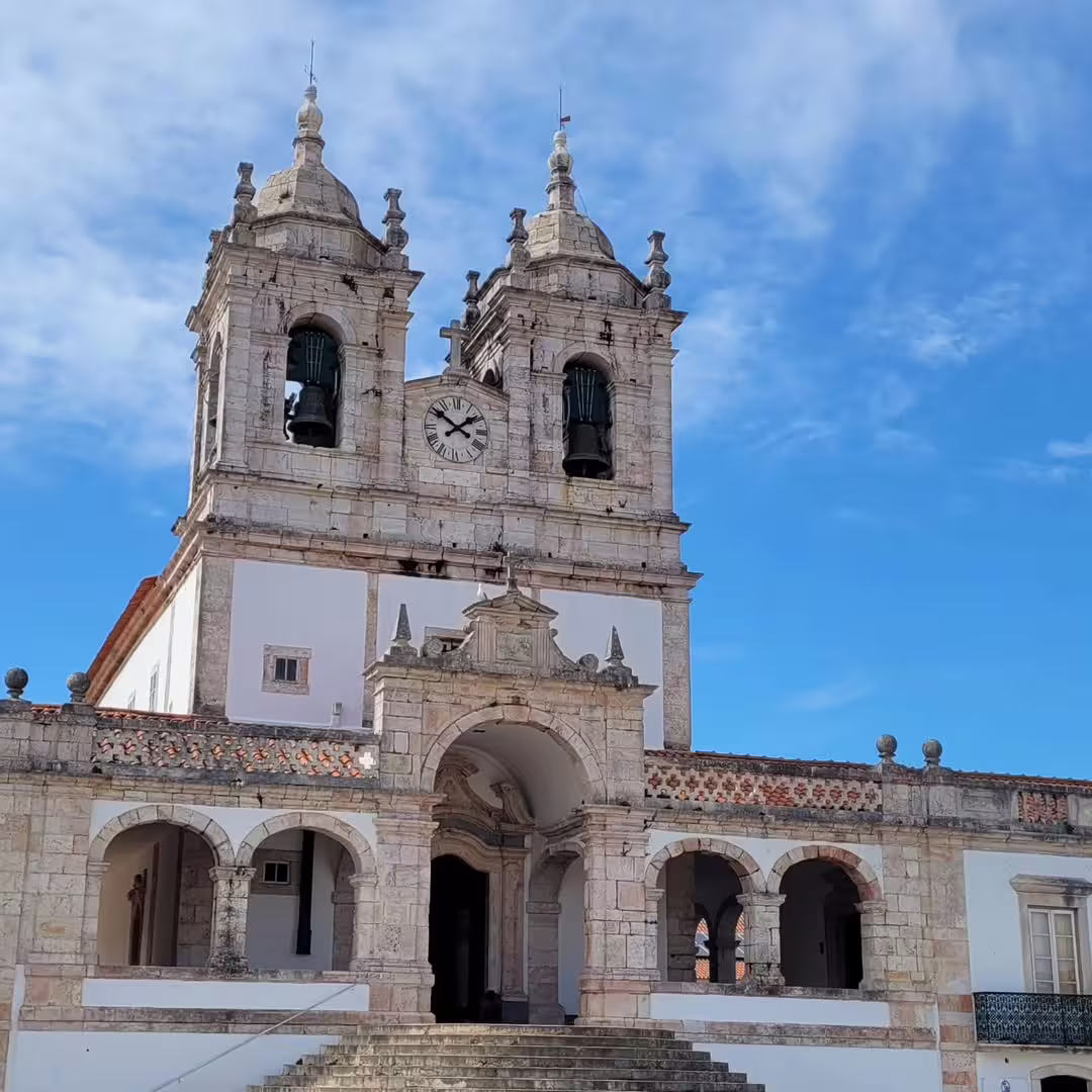 Historic church in Nazaré, Portugal, with stunning architecture under a blue sky—perfect for sightseeing before giant wave surfing.