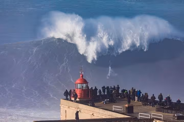 Dramatic waves crashing near the lighthouse at Nazaré, a famous surfing spot included in the Fátima, Batalha, Nazaré, and Óbidos tour.