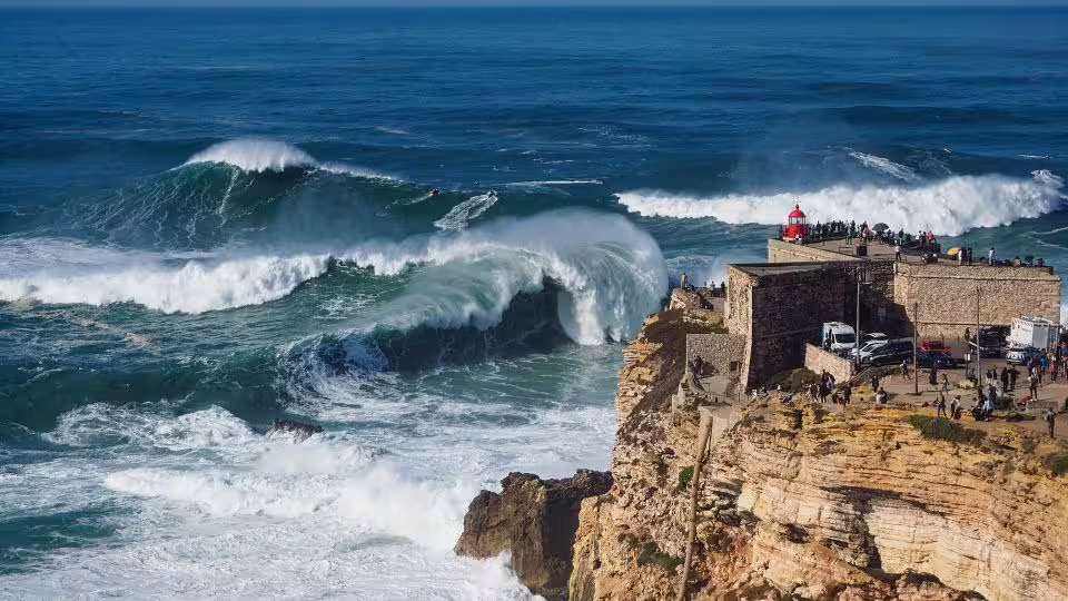 Majestic waves crashing against the cliffs of Nazaré, showcasing the dramatic Atlantic coast on the guided Portugal tour.