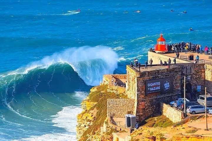 Spectacular Nazaré waves crashing near the iconic lighthouse, ideal for thrilling private coastal tours in Portugal.