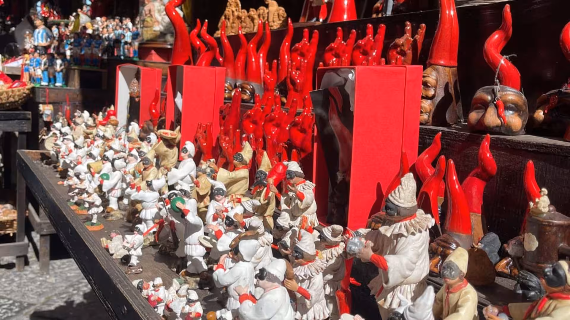 Colorful display of traditional Neapolitan figurines and red cornicelli at a Spaccanapoli market stall.