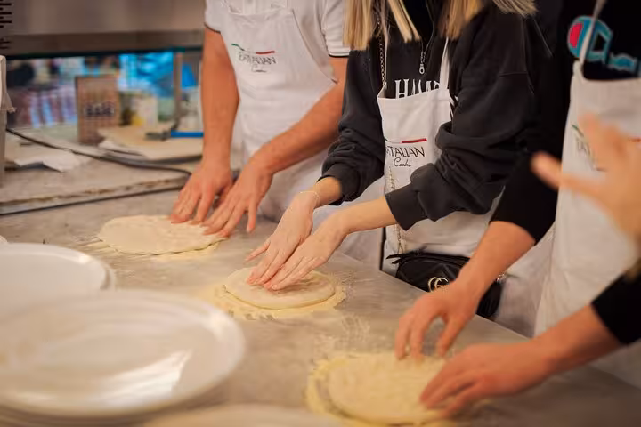 Participants shaping pizza dough during a hands-on cooking class near Piazza Navona in Rome city center.