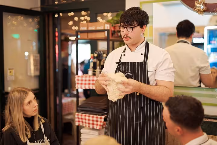 Chef demonstrating dough preparation in a pizza class at Rome's Piazza Navona, engaging participants in hands-on learning.