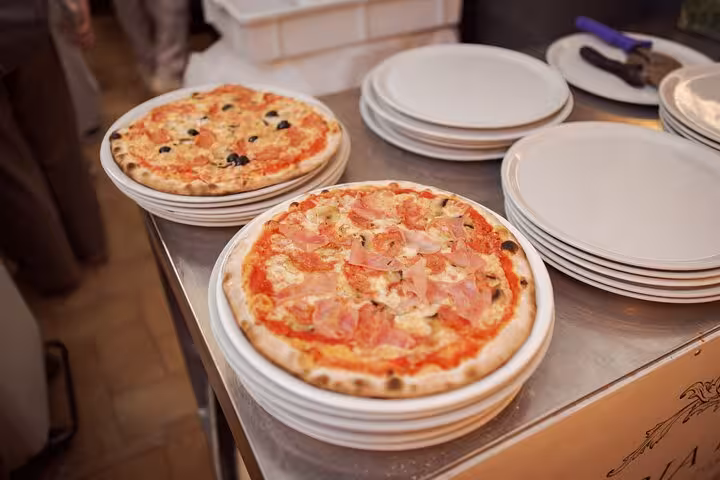 Chef instructing a group during a pizza cooking class in Rome's Piazza Navona, highlighting authentic Italian culinary skills.