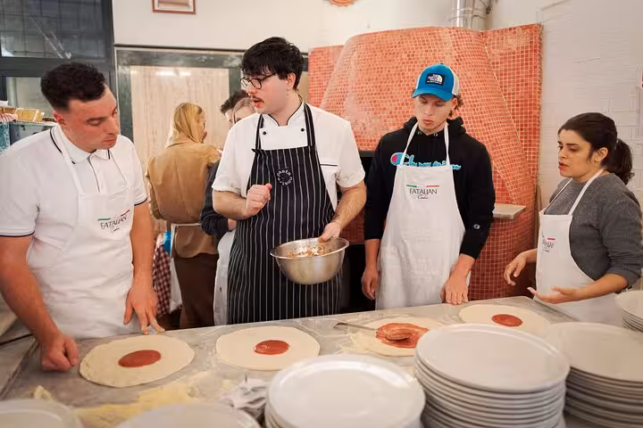 Participants learn pizza-making techniques from a chef at a cooking class near Piazza Navona, Rome City Center.